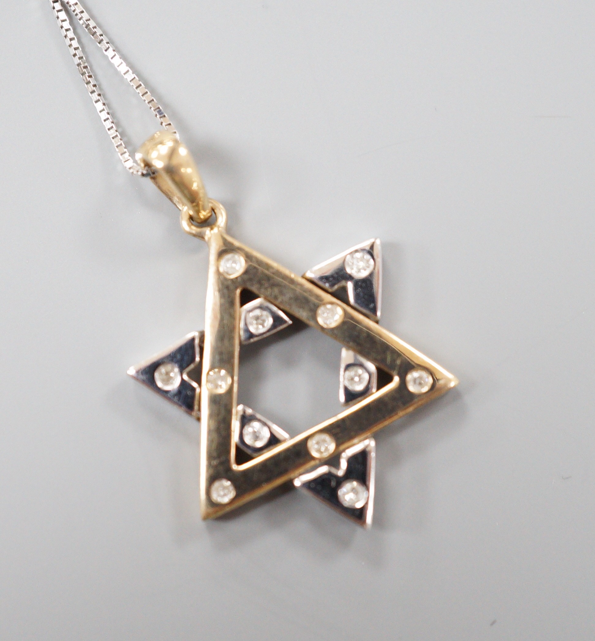 A modern two colour 9ct gold and diamond chip set 'Star of David' pendant, overall 25mm, on a 375 white metal fine link chain, 40cm, gross weight 2.8 grams.